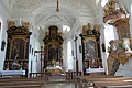 Blick in die helle, lichtdurchflutete Schlosskirche. Vorne in der Mitte der Hauptaltar, links und rechts die Seitenaltäre sowie ganz rechts im Bild die Kanzel.