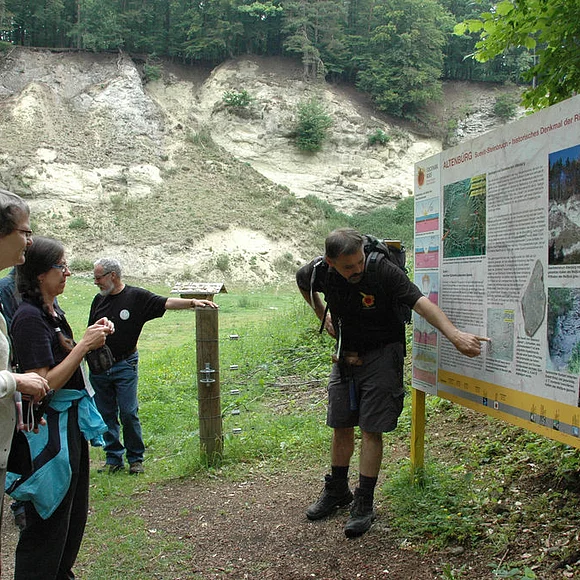 Geopark Führung im Steinbruch Alte Bürg Ein Geoparkführer an der Infotafel bei der Alten Bürg mit Teilnehmern einer Geopark-Führung