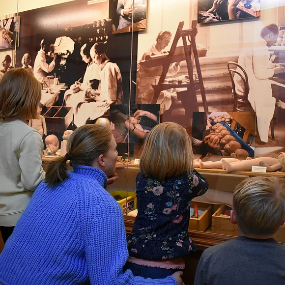 Frau erklärt Kindern im Rahmen einer Familienführung die Schaukästen.