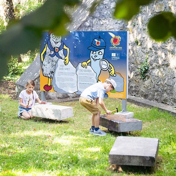 Kinder spielen an der Kinder-Erlebnisstation am Kreuzgraben mit Klangsteinen.