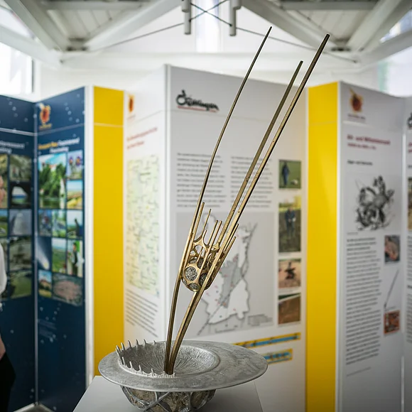 Geopark-Ries Juni 2022 Eine Skulptur zeigt einen Asteroiden vor dem Einschlag in die Erdoberfläche. Im Hintergrund betrachtet ein Mädchen verschiedene Informationstafeln.