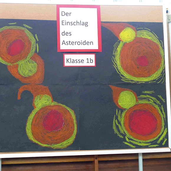 An einer Pinnwand hängen von der Klasse 1b gemalte Bilder des Asteroideneinschlags.