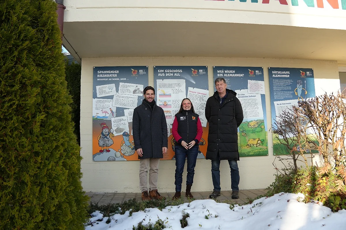 Danyel Atalay, Heike Burkhardt und Siegfried Scholz stehen vor Informationstafeln für Kinder, die an einer Hauswand angebracht sind.