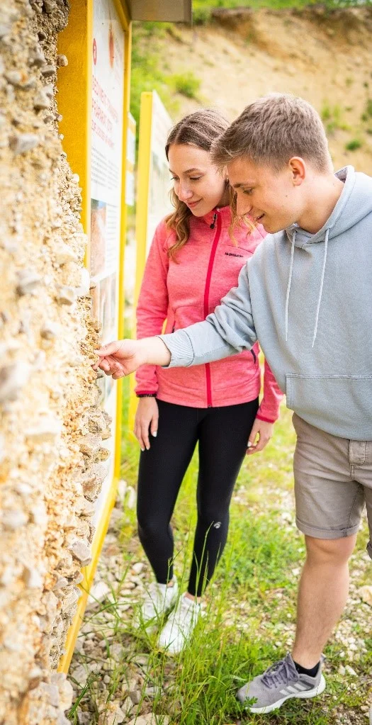 Eine Frau und ein Mann betrachten ein an einer Informationstafel befestigtes Sediment-Transfer-Präparat.