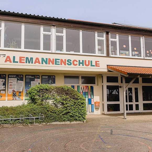 Ein zweistöckiges Gebäude mit hohen Fenstern trägt die Aufschrift "Alemannenschule".