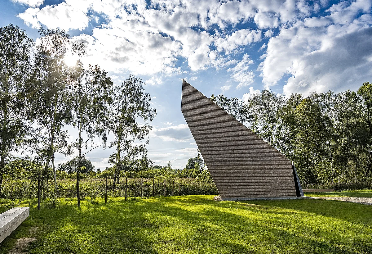 Blick auf die zwischen Bäumen liegende, moderne Kapelle, deren Form an zum Gebet gefaltete Hände erinnern soll.