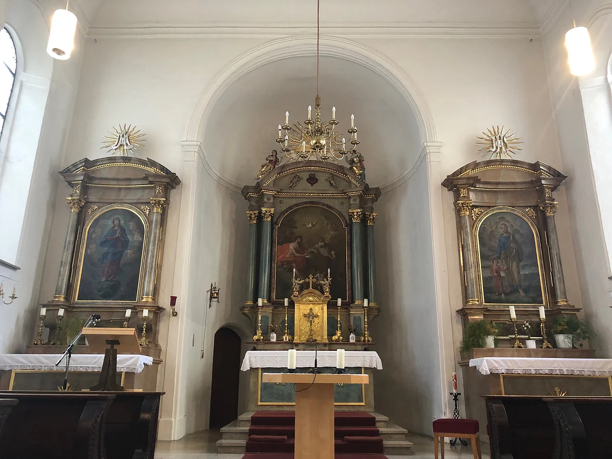 Spitalkirche Blick auf den Innenraum der Spitalkirche, mit Hauptaltar und zwei Seitenaltaren.