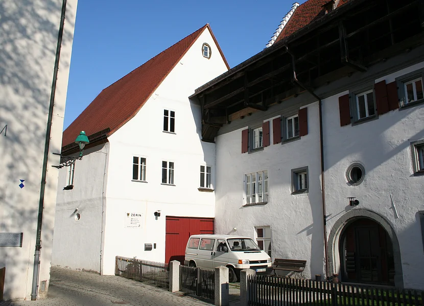 ZERIN, Nördlingen Neben dem Tor eines Hauses mit weißer Fassade hängt ein Schild mit der Aufschrift "ZERIN". Es ist unmittelbar an ein anderes Haus angebaut.