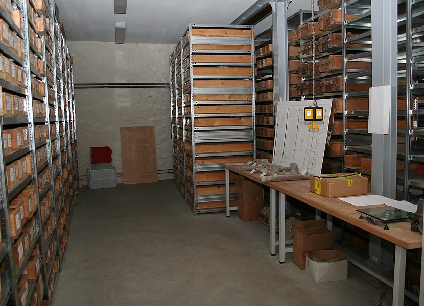 Bohrkern-Archiv In einem Raum stehen mehrere Metallregale mit Holzkästen, die beschriftete Bohrkerne enthalten.