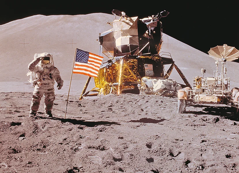 Mondlandung Apollo-Mission Ein Astronaut steht neben einer USA-Flagge auf der Mondoberfläche. Im Hintergrund sind zwei Mondrover zu sehen.