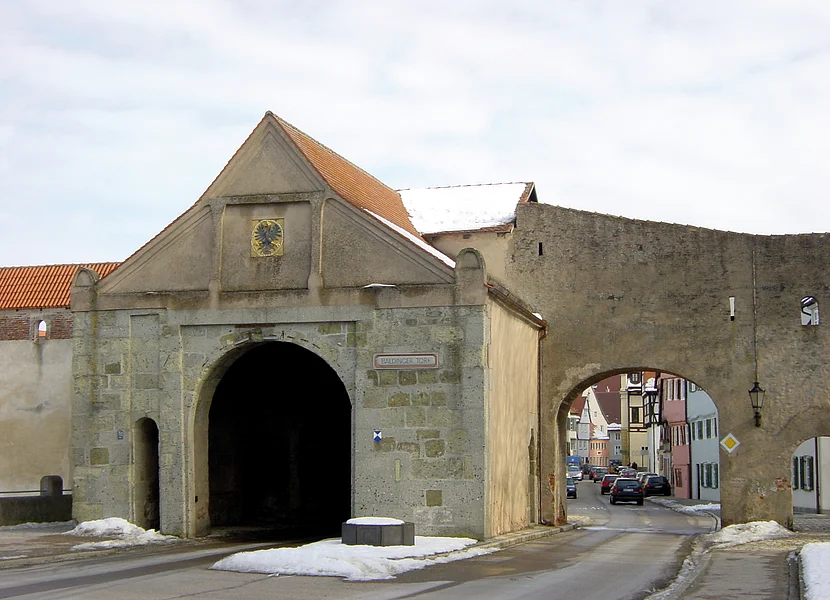 Baldinger Tor, Nördlingen Die zwei Spuren einer Straße führen unter einem Stadttor mit Giebel und der sich anschließenden Stadtmauer hindurch.