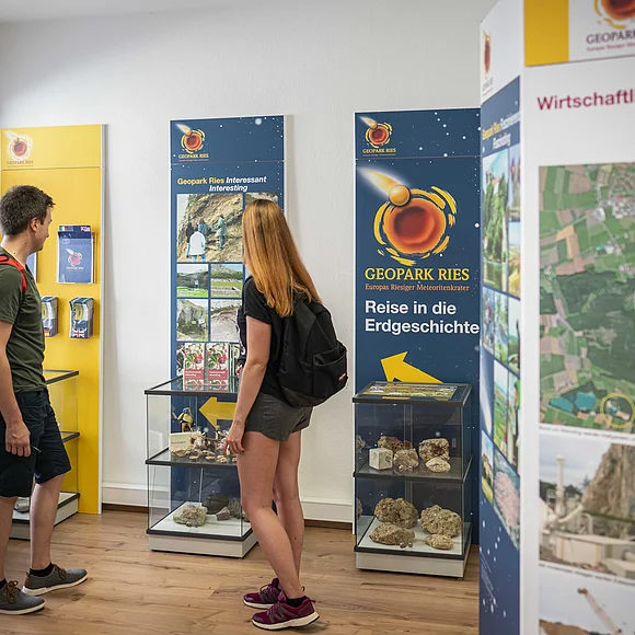 Zwei Besucher, die sich die Informationspanels und Schaukästen in der Geopark Ries Infostelle Wemding ansehen.