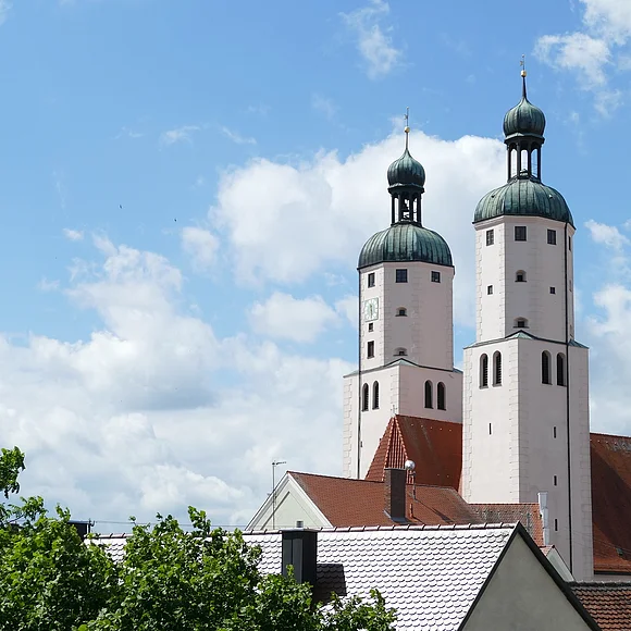 Blick auf die Türme der Stadtpfarrkirche mit weiß blauem Himmel
