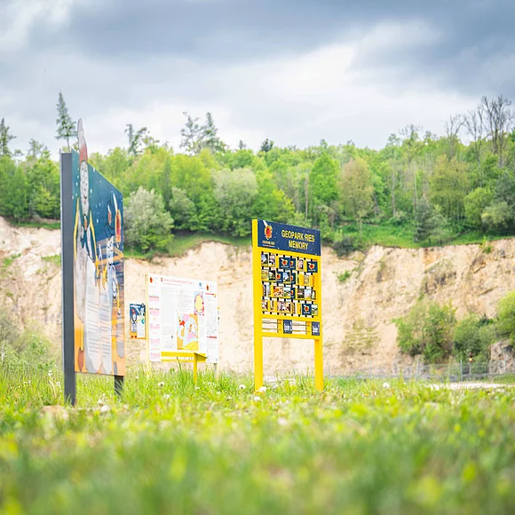 Infotafeln und Memory im Erlebnis-Geotop Lindle. Im Hintergrund ist eine Felswand zu erkennen.