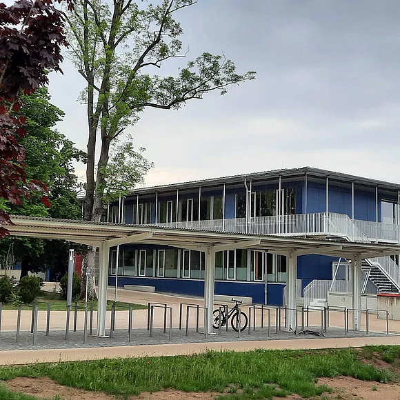 Grund- und Mittelschule Oettingen Seitenansicht der Rückseite der Oettinger Grund- und Mittelschule. Im Vordergrund der überdachte Fahrradständer mit einem Fahrrad.