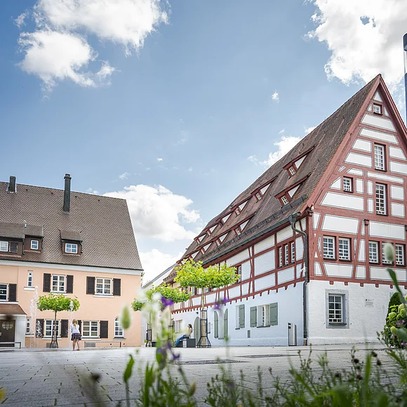 Museum im Seelhaus, Bopfingen Fachwerkhaus mit rotem Giebel und weißen Wänden, daneben ein helles Gebäude, blauer Himmel im Hintergrund.