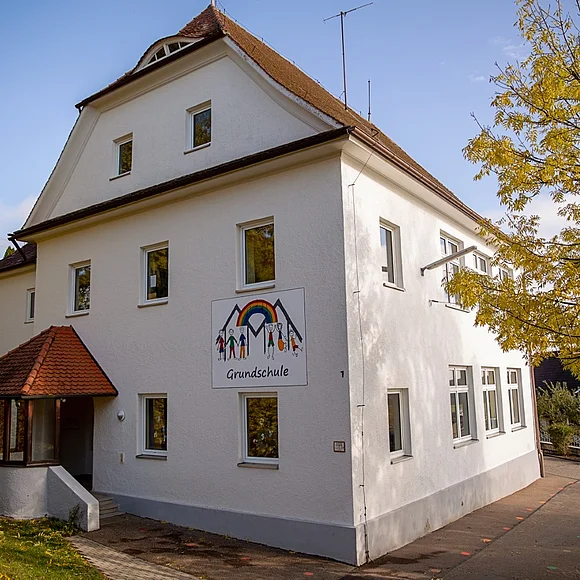 Das Bild zeigt das zweistöckige, weiße Schulhaus der Grundschule Marktoffingen.