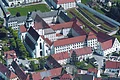 Luftaufnahme eines historischen Gebäudekomplexes mit Kirche, umgeben von Wohnhäusern und Straßen.
