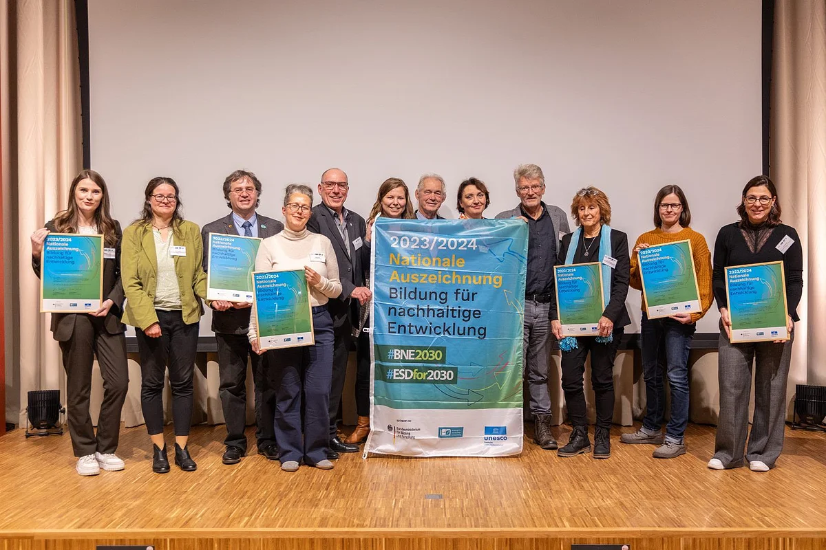 Gruppenfoto mit Vertreter:innen von Geoparks. Einige Personen halten ein Banner mit der Aufschrift "Nationale Auszeichnung - Bildung für nachhaltige Entwicklung".