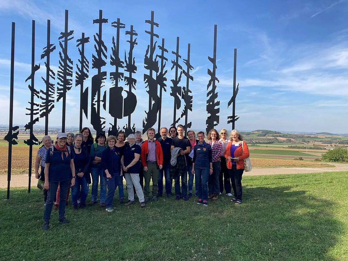 Eine große Gruppe Personen steht am Rand des Rieskraters vor einem Kunstwerk, das ein großes Auge darstellt.