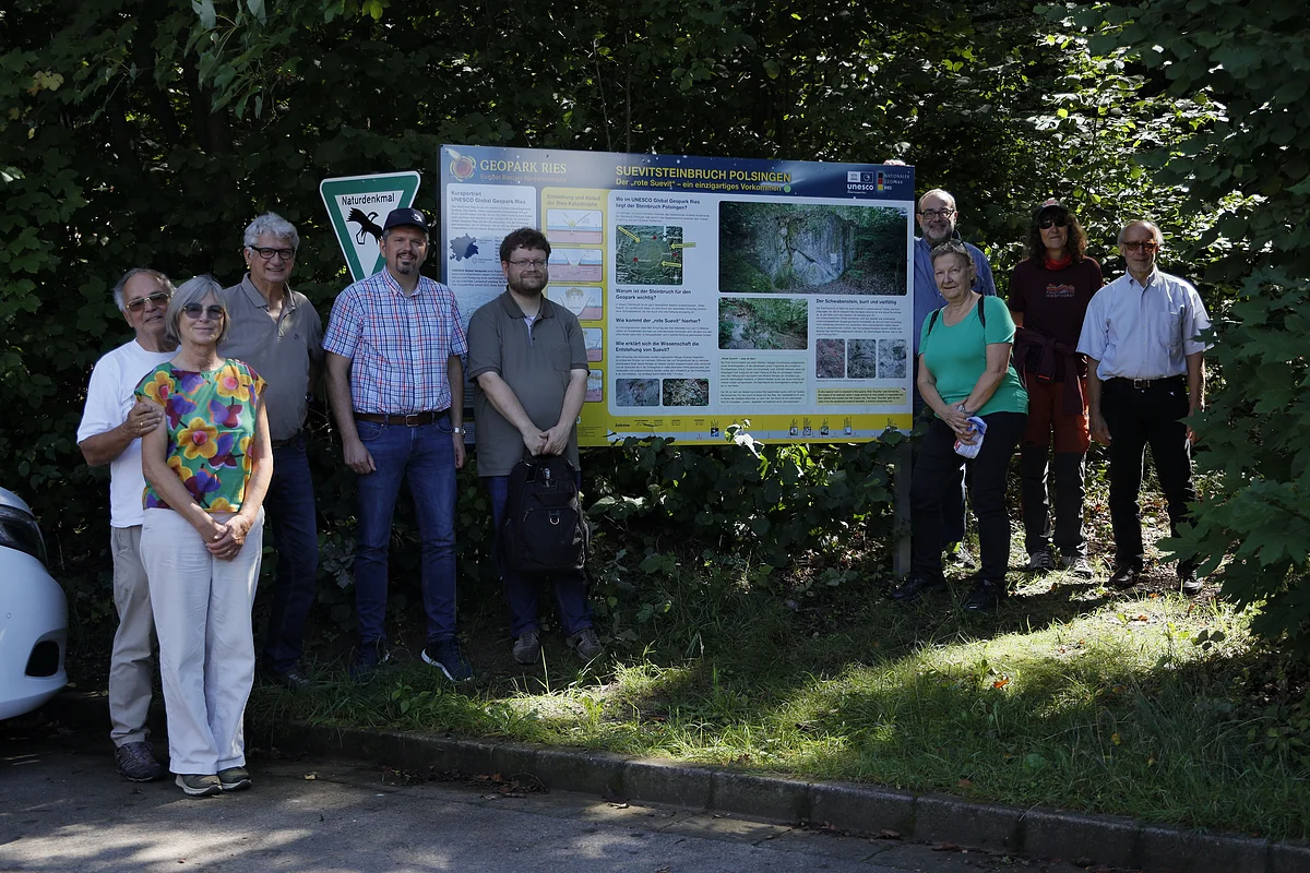 Mehrere Personen stehen neben einer Informationstafel mit der Überschrift "Suevitsteinbruch Polsingen".