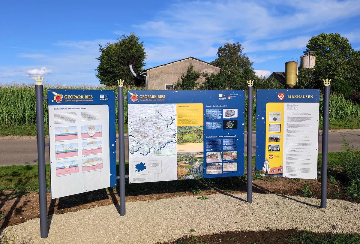 Neben einer Straße stehen drei Informationstafel über den Geopark Ries und die Gemeinde Birkhausen.