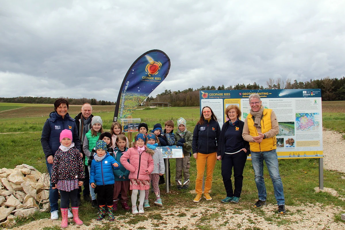 Gruppenfoto mit Vertreter:innen des Geoparks, Daitings Bürgermeister und Kindern bei einer Informationstafel.