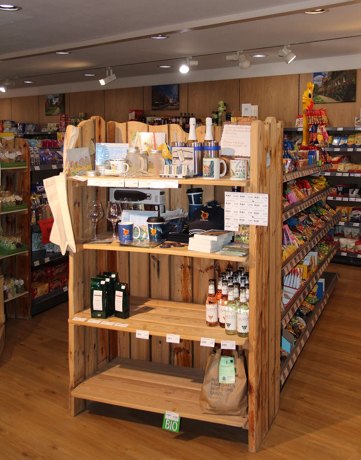 In einem Holzregal stehen verschiedene Merchandise-Artikel mit dem Logo des Geopark Ries.