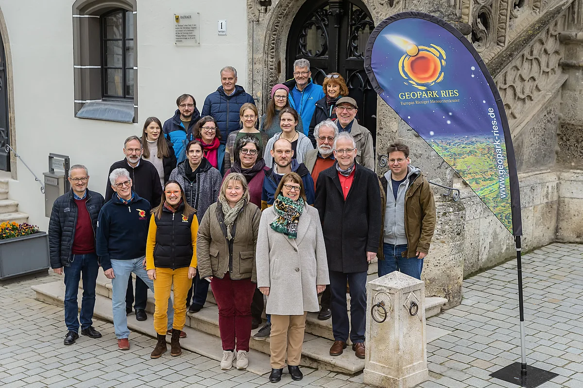 Eine große Gruppe Personen steht auf den Stufen vor einem Portal.
