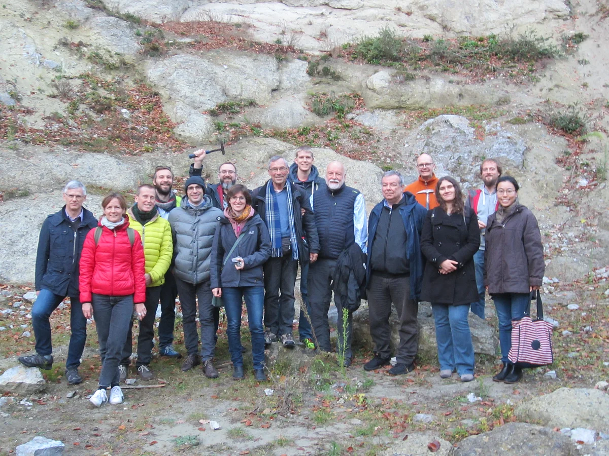 Eine Gruppe Personen steht vor einem felsigen Hang.