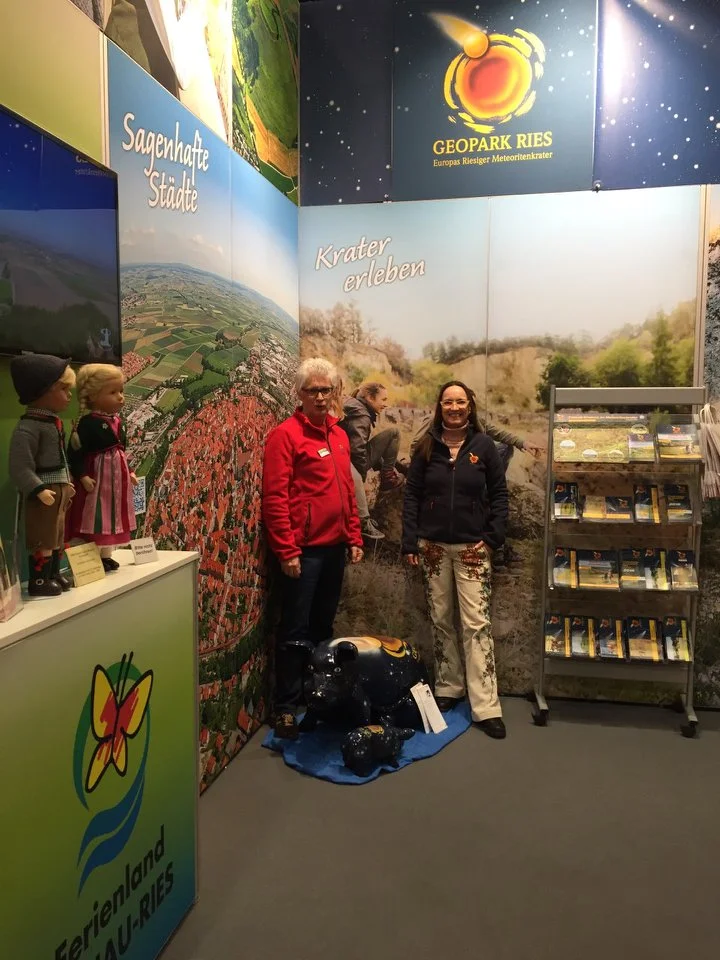 Eine Frau und ein Mann stehen vor dem gemeinsamen Messestand von Geopark Ries und Ferienland Donau-Ries.