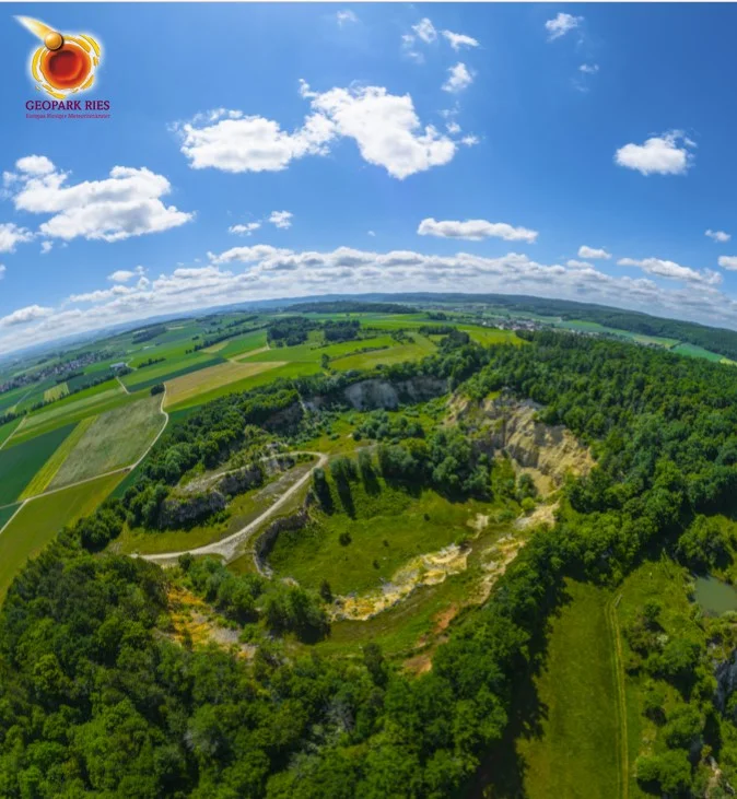 Fischaugenaufnahme eines ehemaligen Steinbruchs, der von Wald umgeben ist.