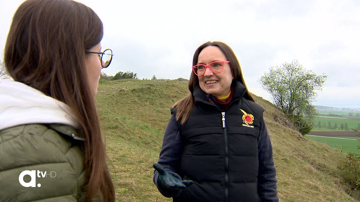Heike Burkhardt steht auf einem Hügel mit Wiese und spricht zu einer Frau.