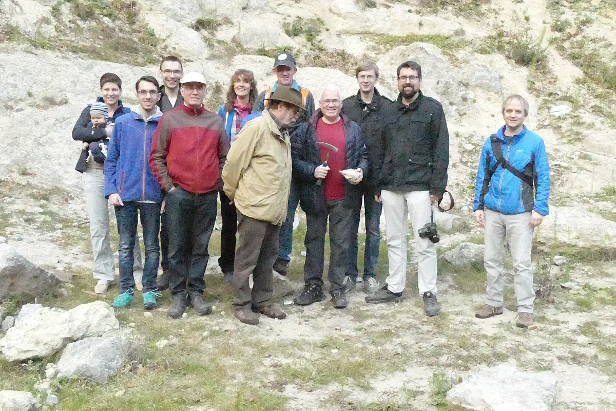 Eine Gruppe Personen steht vor einem felsigen Hang.