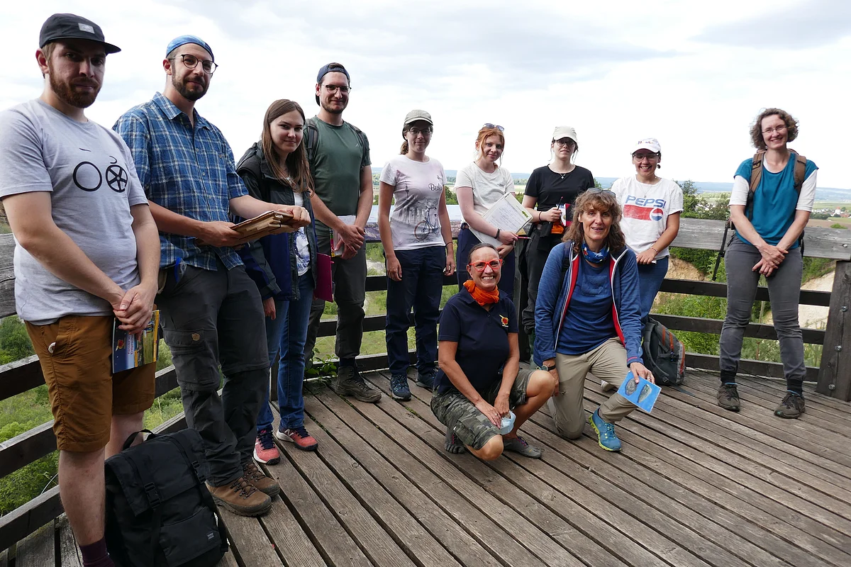 Eine Gruppe Personen steht auf einer hölzernen Aussichtsplattform.