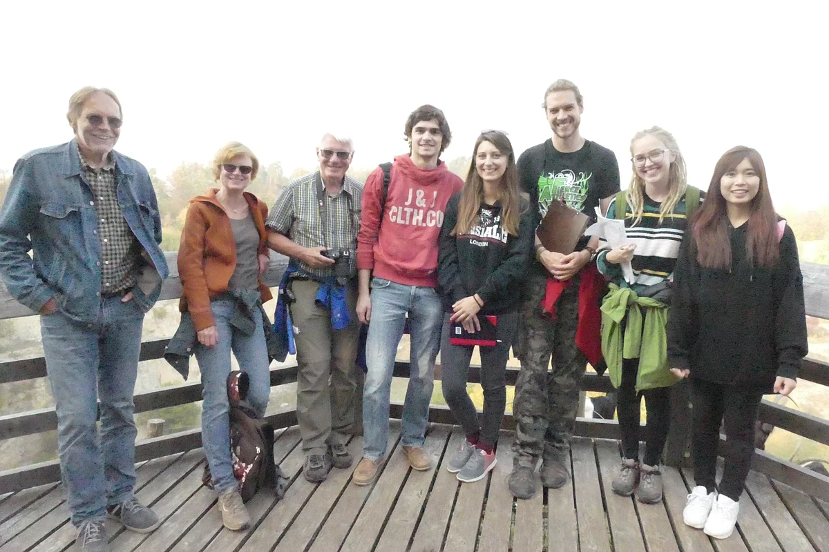 Eine Gruppe Personen steht auf einer Aussichtsplattform aus Holz.