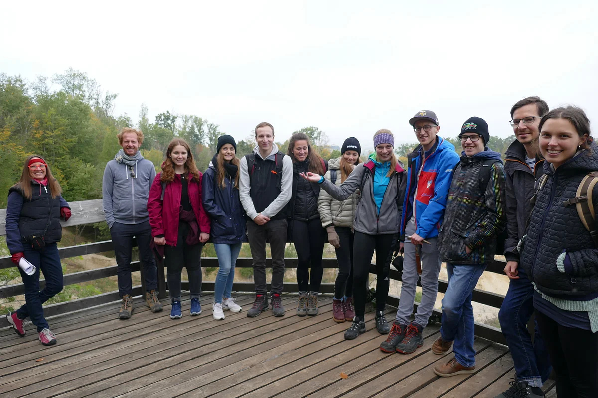 Eine Gruppe Personen steht auf einer hölzernen Aussichtsplattform.