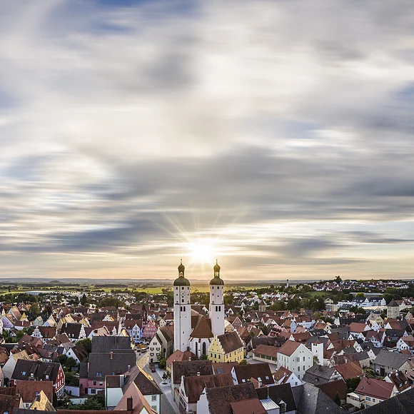 Wemding und Donau-Ries Panoramablick auf Stadt mit roten Dächern und zwei Kirchtürmen bei Sonnenuntergang unter bewölktem Himmel
