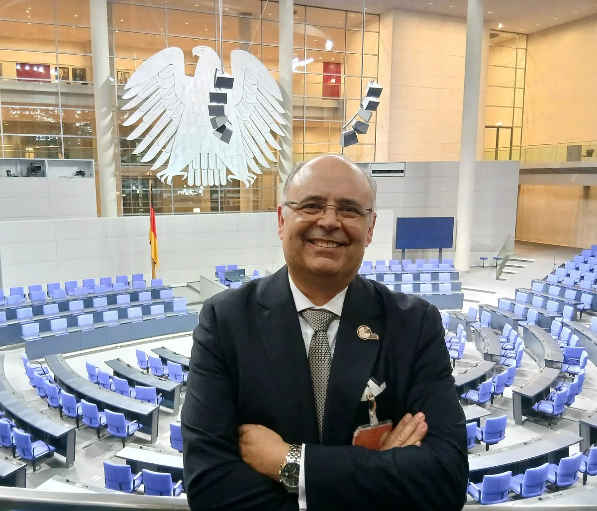 Artur Sá Artur Sá (Vorsitzender GGN) steht vor den Sitzreihen im Deutschen Bundestag. Im Hintergrund der Bundesadler.