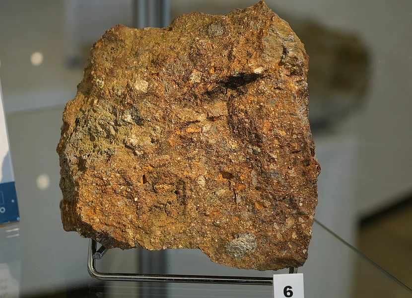Hämatitreicher Suevit aus dem Steinbruch Aumühle Zu sehen ist ein rötlich wirkendes Stück Suevit. Davor die Nr. 6.
